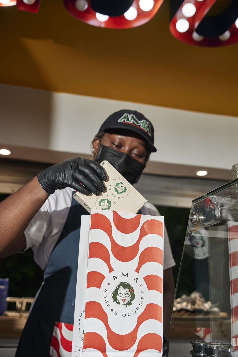 Alguien del equipo de Amá entregando un pedido en la bolsa de la marca