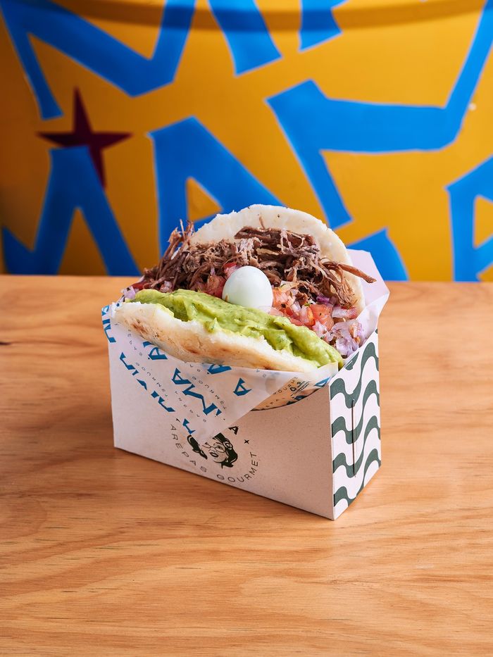 Arepa Amá sobre fondo gráfico de la marca